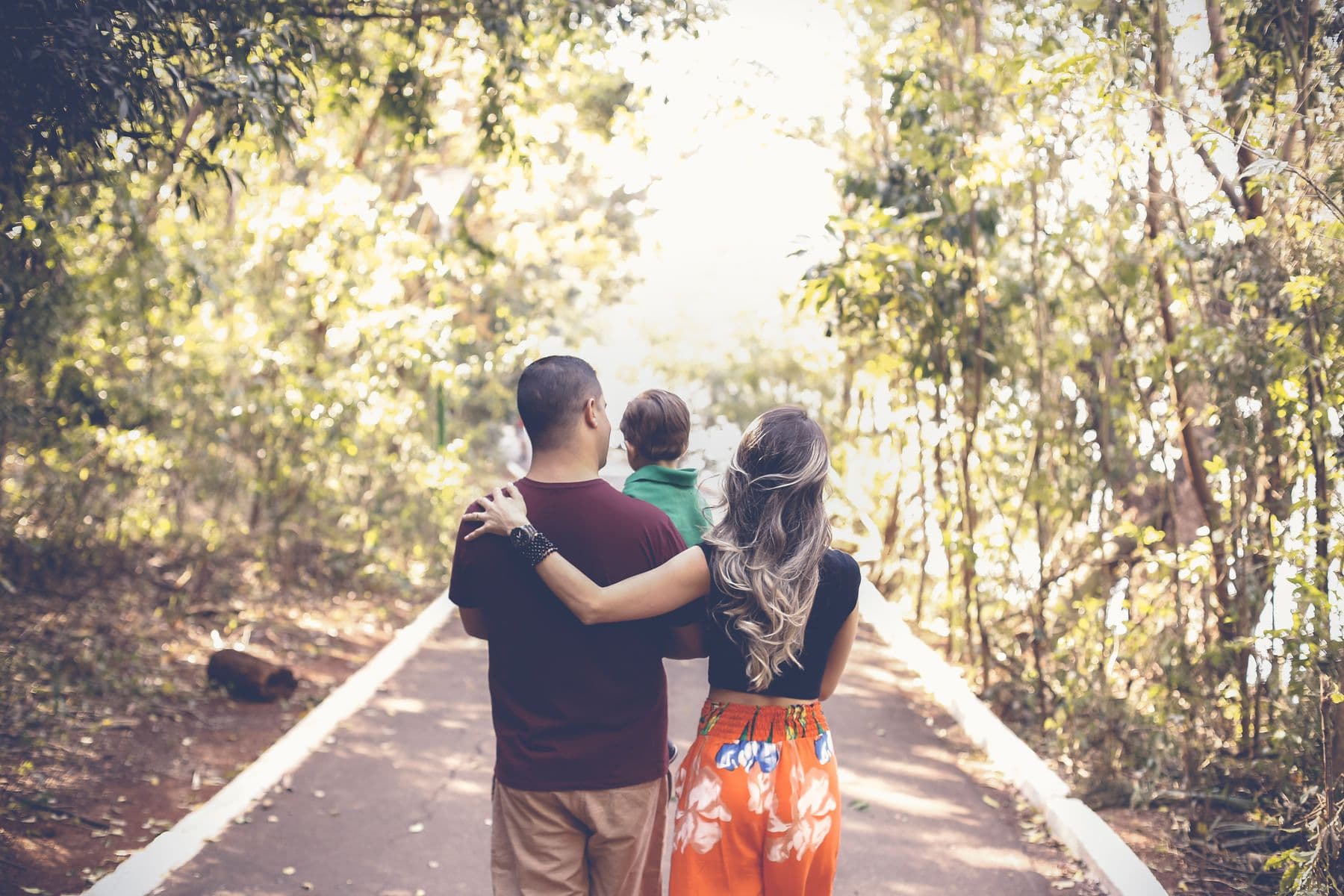 A family walks together along a tree-lined path.